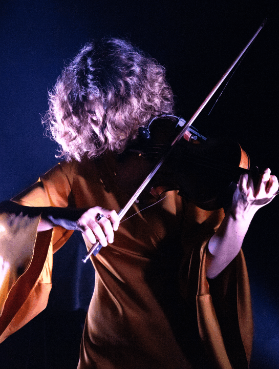 Anna Milman con su violín bajo luces de escenario